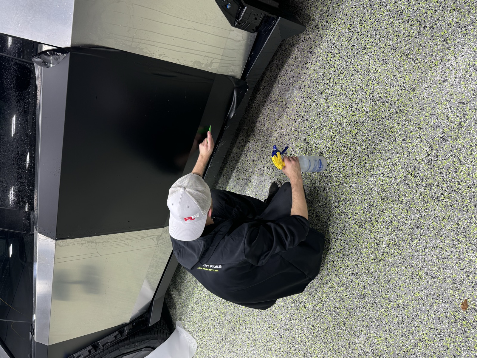 Revolutionary Rides installer squeegeeing film onto a Tesla Cybertruck panel