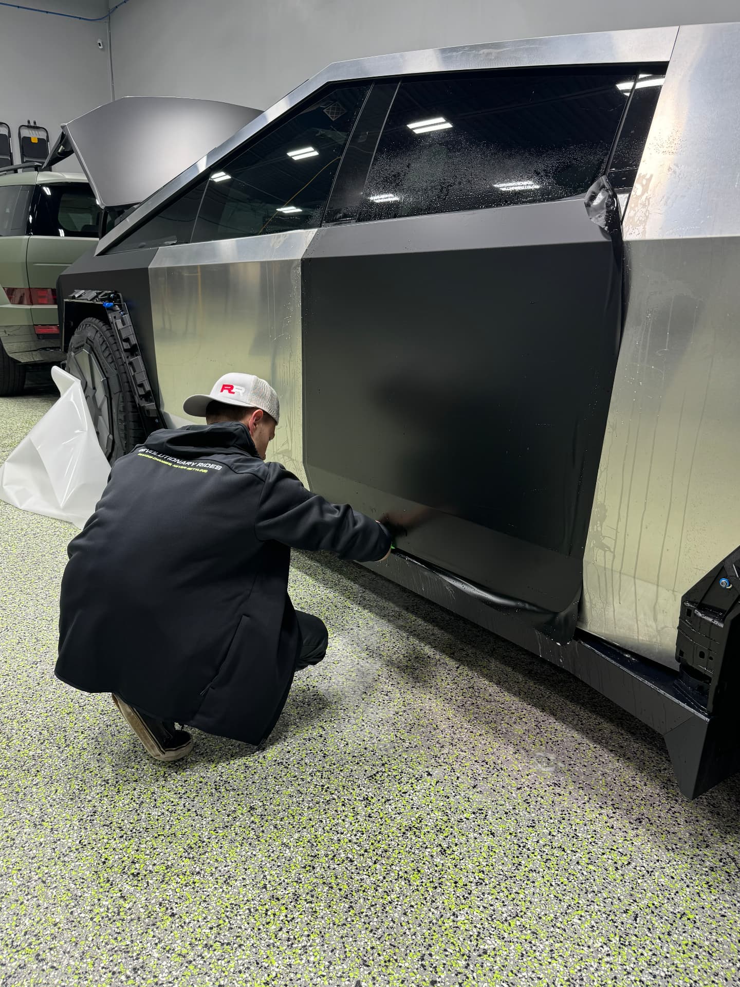 Revolutionary Rides technician wrapping a Tesla Cybertruck door panel in the shop